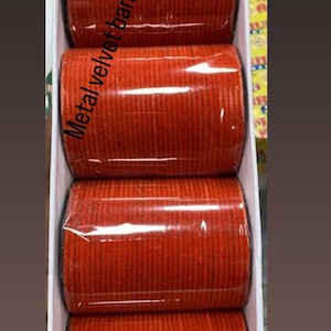 May include: A set of four orange metal velvet bangles in a white box. The bangles are stacked on top of each other and are wrapped in clear plastic. The text "Metal velvet bangles" is printed on the box.