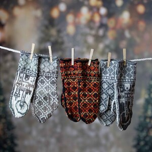 May include: Five knitted wool mittens hanging on a washing line with wooden pegs. The mittens are in various patterns and colours, including grey, white, and red.