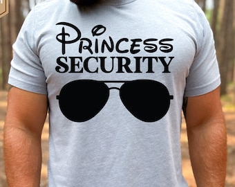 Op de afbeelding: Een lichtgrijs heather t-shirt met een zwarte afbeelding van een zonnebril en de tekst "Princess Security" in een Disney-stijl lettertype.