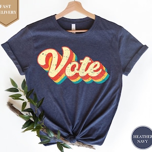 May include: A navy blue t-shirt with a vintage-style "Vote" graphic in red, yellow, green, and blue.