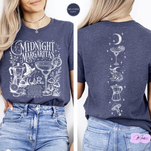 a woman wearing a blue t-shirt with a graphic design depicting a nighttime margarita scene.