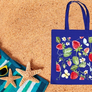 a blue shopping bag sitting on top of a sandy beach