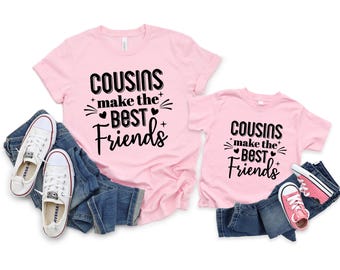 Könnte beinhalten: Zwei rosa T-Shirts mit dem Text "Cousins make the Best Friends" in schwarzer Schrift. Die Shirts sind mit blauen Jeans und weißen Leinenschuhen kombiniert. Ein kleineres rosa Shirt und Jeans mit rosa Turnschuhen sind ebenfalls enthalten.