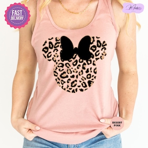 May include: A light pink tank top featuring a leopard print Minnie Mouse design with a black bow. The tank top has a round neckline and is made of a soft material. The words "Fast Delivery" are on a pink sticker in the upper left corner.