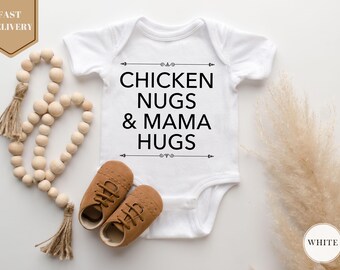 May include: White baby onesie with the text "CHICKEN NUGS & MAMA HUGS" in black. The image includes brown baby shoes and a wooden bead garland with tassels. A beige floral element is on the right.