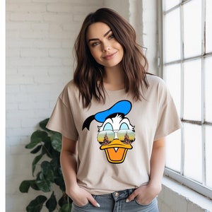 a woman standing next to a window wearing a t - shirt with a donald duck