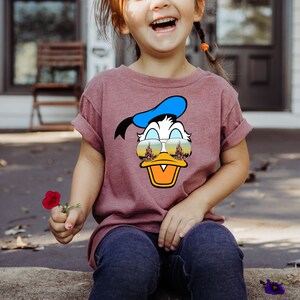 a little girl sitting on the ground with a flower in her hand