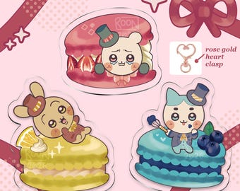 Könnte beinhalten: Acryl-Macaron-Anhänger mit Cartoon-Charakteren mit Zylindern. Die Anhänger haben die Form von Macarons mit Erdbeer-, Zitronen- und Blaubeerfüllungen. Der Text "chii x macaron charms" und "stepharoon's" sind sichtbar.