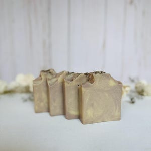 Puede incluir: Un juego de tres tazas de cerámica con un esmalte moteado de color crema. Cada taza presenta un diseño pintado a mano diferente: una hoja azul y verde, una flor amarilla y una baya roja. Las tazas tienen una forma simple y redondeada.