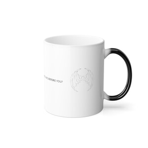 May include: White ceramic mug with a black handle. The mug features a black bat-like creature with wings on the front. The text "RELIGION BEFORE YOU?" is printed on the mug.