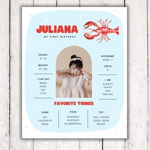 May include: A blue and white printable first birthday card with a photo of a baby girl, a lobster illustration, and the text "Juliana, My First Birthday". The card includes details about the baby's height, weight, nickname, teeth, what they can say, and their favorite things.