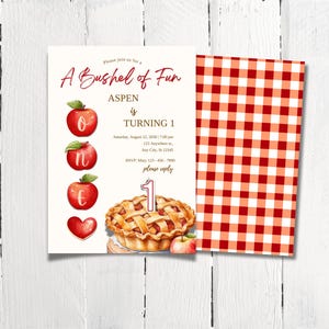 K&ouml;nnte beinhalten: Ein rot-wei&szlig; karierter Hintergrund mit einer wei&szlig;en Einladungskarte. Die Einladungskarte hat ein rotes Apfel-Motiv und lautet "A Bushel of Fun Aspen is Turning 1" mit einem Kuchen und einer Kerze.