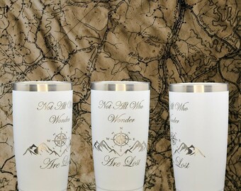 May include: Three white stainless steel tumblers with a silver inscription that reads "Not All Who Wonder Are Lost". Each tumbler features a compass and mountain graphic.