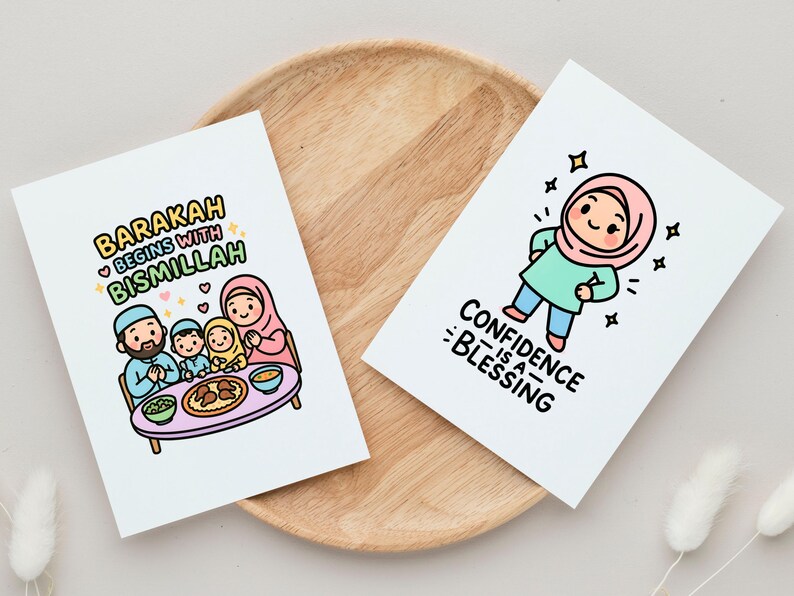 May include: Two white cards with colorful illustrations and text. One card says "Barakah begins with Bismillah" with a family illustration. The other card says "Confidence is a Blessing" with a cartoon character. Both cards are on a wooden tray.