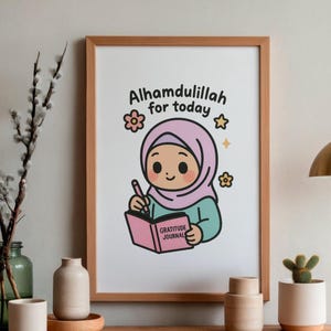 May include: A framed print featuring an illustration of a cartoon girl wearing a pink hijab, writing in a pink "Gratitude Journal." The text "Alhamdulillah for today" is above the girl. The print is in a wooden frame.