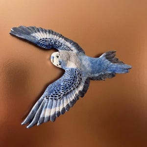 May include: A blue and white decorative bird sculpture with outstretched wings. The bird has detailed feather patterns and is set against a copper-coloured background. The sculpture is designed to appear as if it is in flight.
