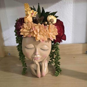 Op de afbeelding: Een witte keramische mok met een zwarte handgreep en de tekst "But First, Coffee" in een vetgedrukte, zwarte letter. De mok staat tegen een vage achtergrond, wat een gezellige setting suggereert.