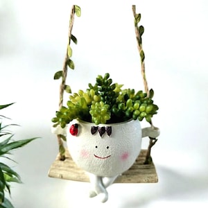Doniczka wisząca „Uśmiechnięta bujana twarz”: żywiczna doniczka w kształcie głowy kobiety z sztucznymi sukulentami