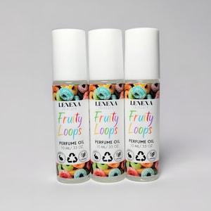 May include: Three clear glass roller bottles with white caps and colorful labels. The labels say "Fruity Loops Perfume Oil 10 ml/ .33 oz" and feature a cartoon design of colorful cereal loops.