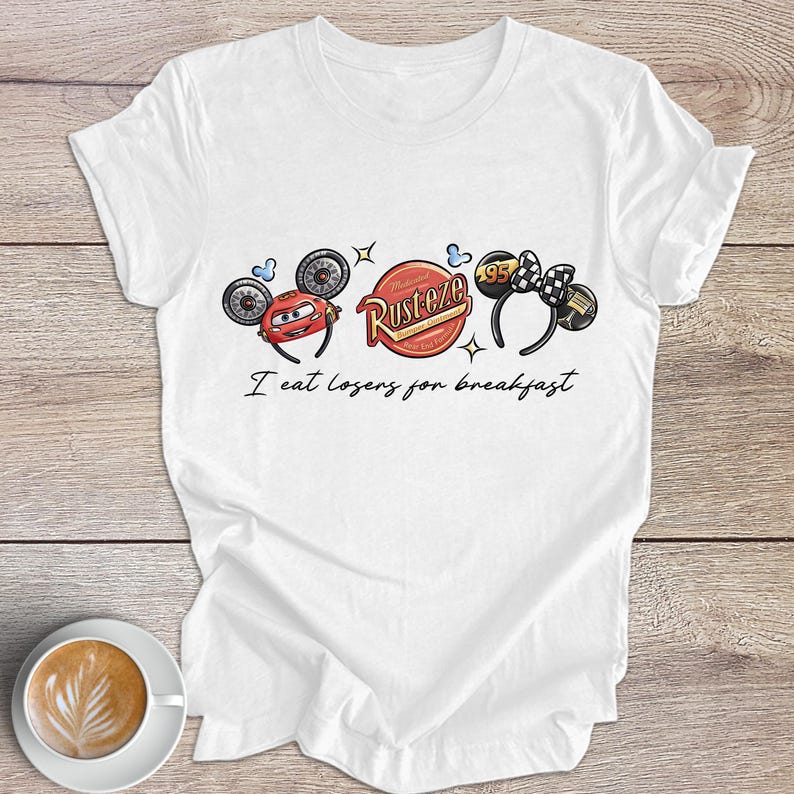 Peut inclure: T-shirt blanc avec un motif de voiture de dessin anim&eacute; et le texte "I eat losers for breakfast". Le design comprend une voiture rouge, un logo "Rusteze" et un n&oelig;ud papillon &agrave; carreaux noir et blanc.