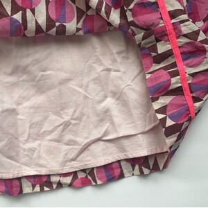 May include: A pink and purple geometric print skirt with a pink trim. The skirt has a pink lining.