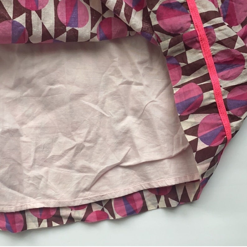 May include: A pink and purple geometric print skirt with a pink trim. The skirt has a pink lining.