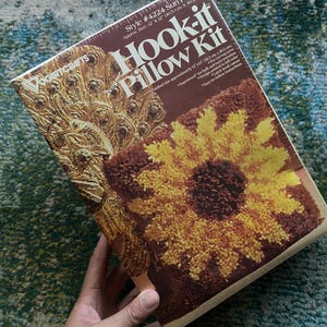 May include: A craft kit for making a sunflower pillow. The kit includes yarn, a latch hook canvas, and instructions. The finished pillow will be approximately 12 inches by 12 inches.