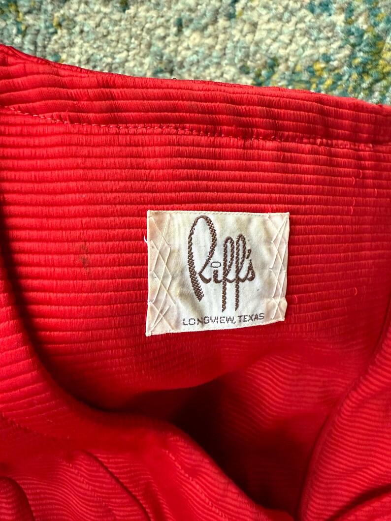 May include: A red ribbed fabric with a white label that says "Riff's Longview, Texas".