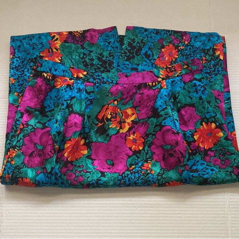 Puede incluir: Una falda de estampado floral colorido con cintura alta y dise&ntilde;o fruncido. La falda est&aacute; hecha de una tela sedosa y presenta una variedad de colores, incluyendo rosa, azul, verde y amarillo.