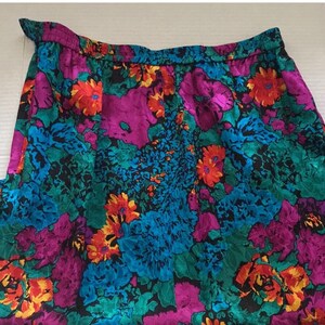 Puede incluir: Una falda floral colorida con fondo negro. La falda tiene una mezcla vibrante de flores rosas, azules, verdes, naranjas y amarillas.