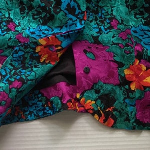 Puede incluir: Primer plano de una tela floral colorida con un bot&oacute;n negro. La tela es una mezcla de rosa, azul, verde y naranja.