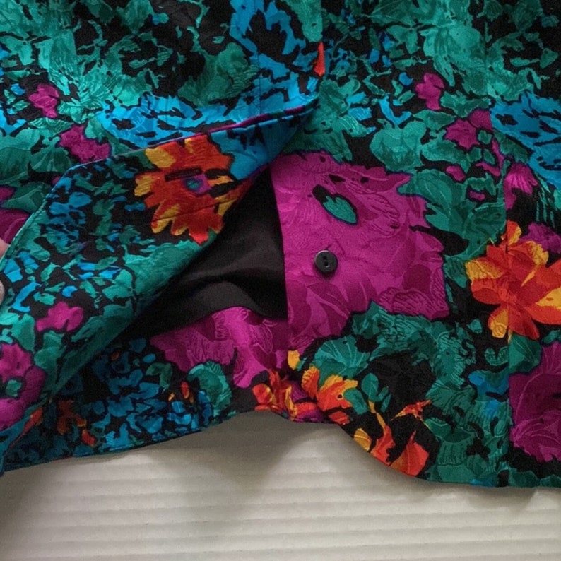 Puede incluir: Primer plano de una tela floral colorida con un bot&oacute;n negro. La tela es una mezcla de rosa, azul, verde y naranja.