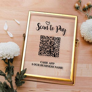 May include: A rectangular clear acrylic sign held in a gold metal frame. The sign features black text that reads Scan to Pay with a heart icon, a central QR code, and the text CASH APP $ OUR BUSINESS NAME printed in a clean, sans-serif font.
