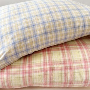 May include: Two plaid pillowcases, one in blue and yellow and the other in pink and yellow.
