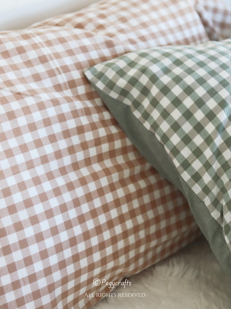 May include: Close-up of two decorative pillows with a gingham pattern. One pillow features a brown and white checkered design, while the other has a green and white checkered pattern. The pillows are soft and inviting, perfect for home decor.
