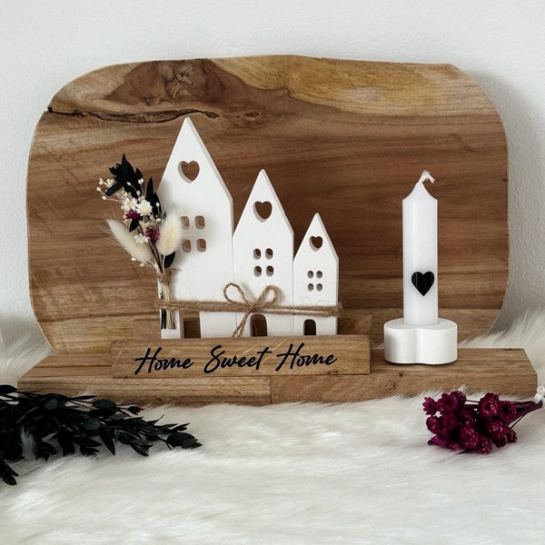Auf einem Holzständer auf dem steht "Home Sweet Home" Häuser und Kerze