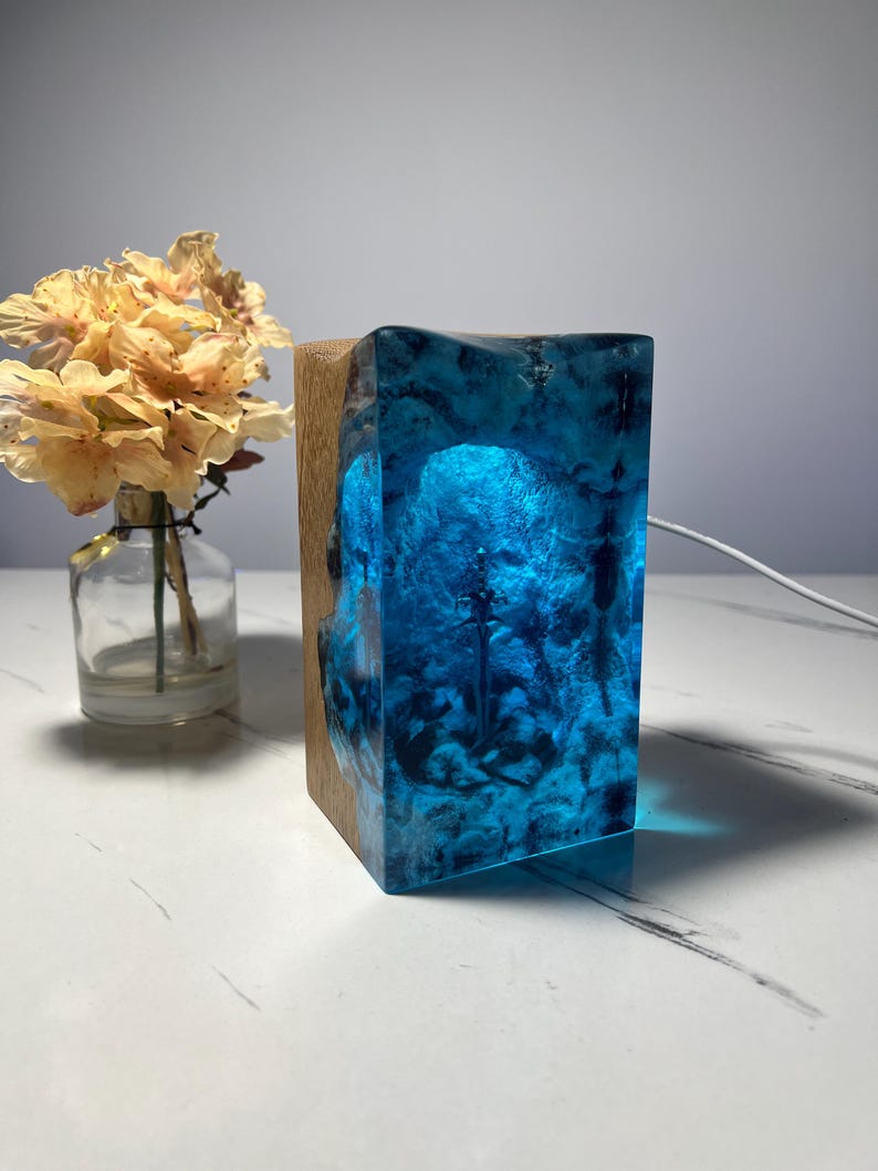 May include: A blue resin lamp with a wood base. The resin has a swirling pattern and is illuminated from within.