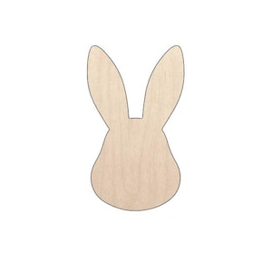 May include: A wooden bunny head cutout with long ears. The bunny is made of light-coloured wood and has a smooth surface. The cutout is ideal for Easter crafts and decorations.