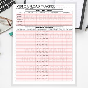 Op de afbeelding: Een wit papier met een roze rasterindeling met de titel "Video Upload Tracker" voor het volgen van de prestaties van video's op sociale media. Het document bevat secties voor upload data, tijden en prestatiegegevens. Een laptop, bril en pen staan op de achtergrond.
