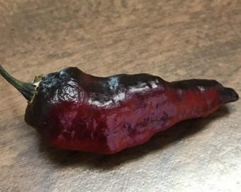 Pode incluir: Um pimentão vermelho escuro com textura enrugada.