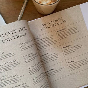 Puede incluir: Un primer plano de una página de libro con el título "2 Leyes del Universo" y una lista de métodos de manifestación, incluyendo la visualización, la escritura y el método 369. La página es beige con texto marrón.