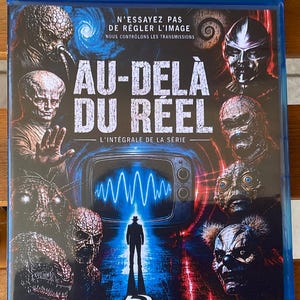 May include: A blue Blu-ray disc case for the television series Au-delà du réel, featuring a central television screen with a blue waveform, a silhouette of a person, and various alien and creature portraits surrounding the title text.
