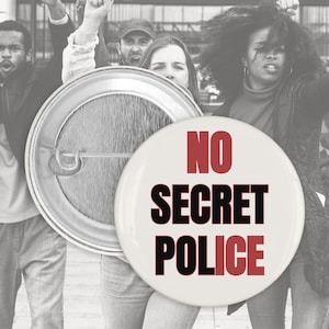 Pode incluir: Um botão branco com as palavras "NO SECRET POLICE" em vermelho e preto. O botão é redondo e tem um alfinete. O fundo mostra um grupo de pessoas.
