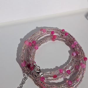 May include: A multi-strand wrap bracelet featuring alternating pink gemstone beads and clear seed beads. The bracelet has a silver-tone clasp and a heart charm at the end of the chain.