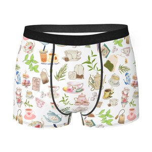May include: White boxer shorts with a black waistband and a pattern of teacups, teapots, tea leaves, and tea bags. The text "PERFECT CUP OF TEA" is printed on the shorts.