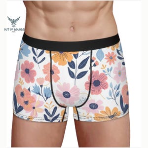 May include: White boxer briefs with a floral print featuring pink, orange, and blue flowers. The waistband is black.