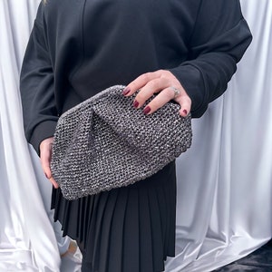 May include: A silver sparkly clutch purse with a gathered design.