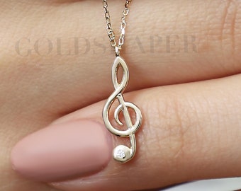 May include: A gold necklace with a treble clef pendant and a small diamond accent.