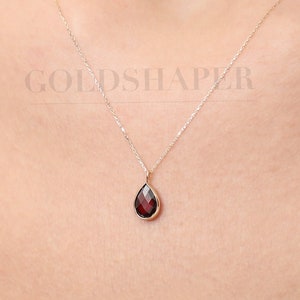 Può includere: Una delicata collana a catena d'oro con un ciondolo a forma di lacrima con una pietra preziosa rossa.