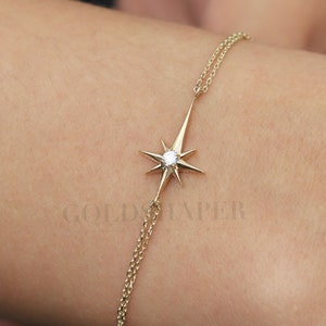 May include: A gold chain bracelet with a star-shaped pendant featuring a small diamond in the center. The bracelet is on a person's wrist.